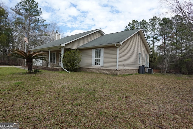 view of front of property featuring brick siding, a chimney, cooling unit, and a front yard