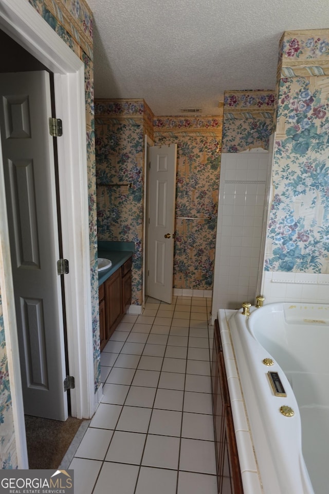 full bathroom with a textured ceiling, tile patterned flooring, vanity, tiled tub, and wallpapered walls