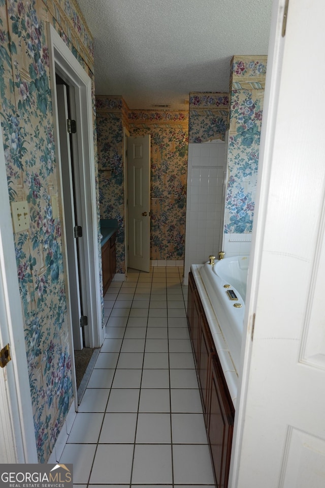 bathroom featuring wallpapered walls, tile patterned flooring, a bathing tub, and a textured ceiling