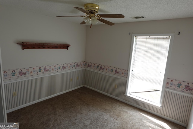 empty room with a wainscoted wall, a textured ceiling, and carpet flooring