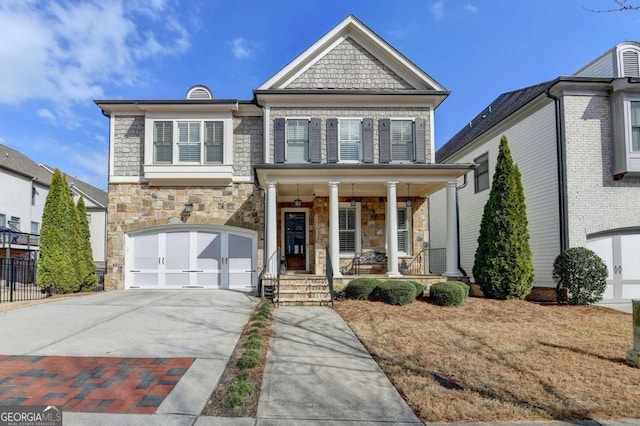 view of front of home with stone siding, covered porch, driveway, and a garage