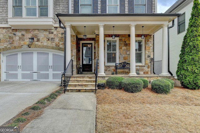 property entrance with a porch, stone siding, concrete driveway, and a garage