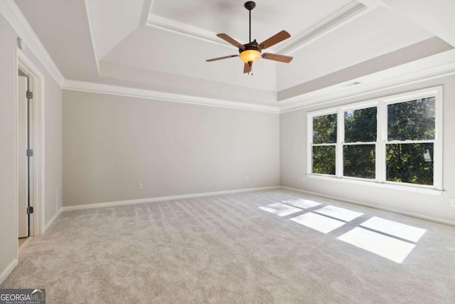 carpeted spare room featuring ceiling fan, visible vents, baseboards, a tray ceiling, and crown molding