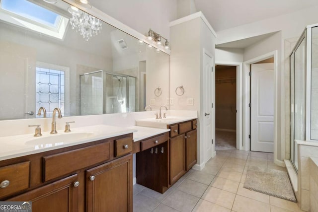 bathroom featuring a skylight, double vanity, a stall shower, a sink, and tile patterned flooring