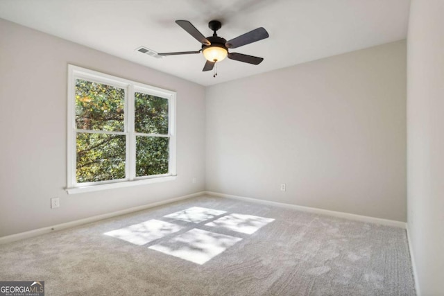 carpeted empty room with a ceiling fan, visible vents, and baseboards