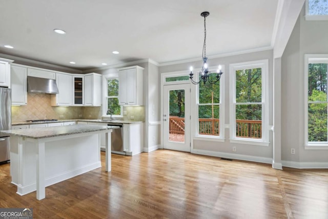 kitchen featuring white cabinets, light wood-style flooring, appliances with stainless steel finishes, light stone countertops, and under cabinet range hood