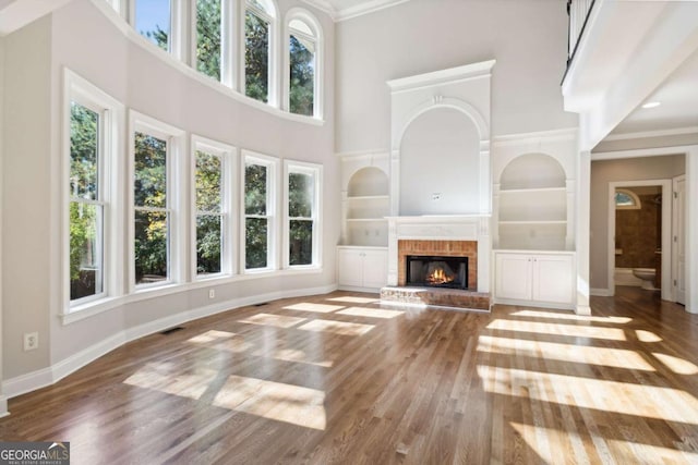 unfurnished living room featuring baseboards, a fireplace, wood finished floors, and built in features