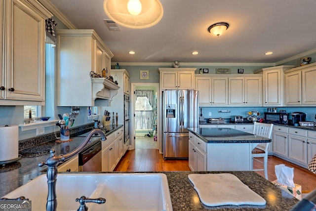 kitchen with visible vents, crown molding, appliances with stainless steel finishes, wood finished floors, and cream cabinetry