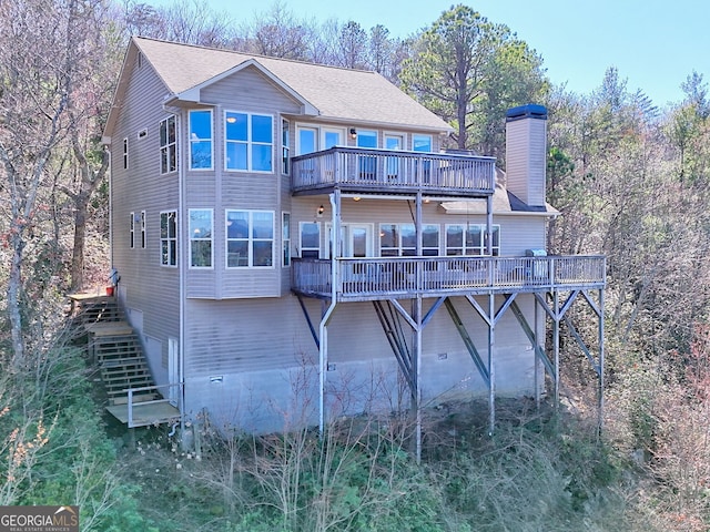 rear view of property with a deck, stairs, and a chimney