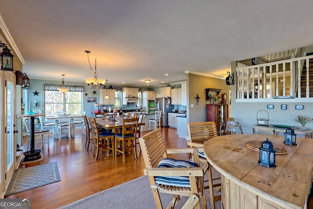 dining space with a chandelier, recessed lighting, ornamental molding, and dark wood-style flooring