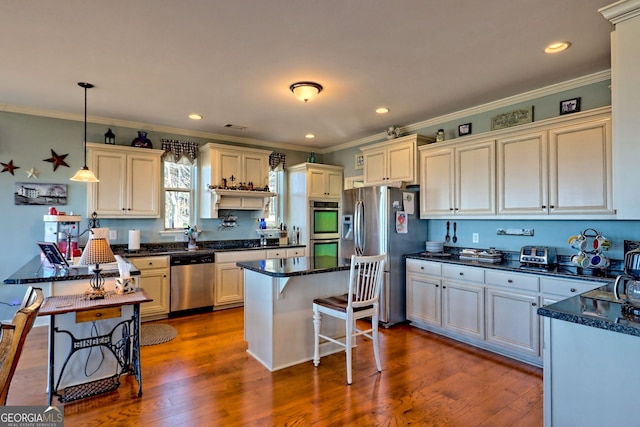 kitchen with dark wood finished floors, ornamental molding, stainless steel appliances, decorative light fixtures, and a center island