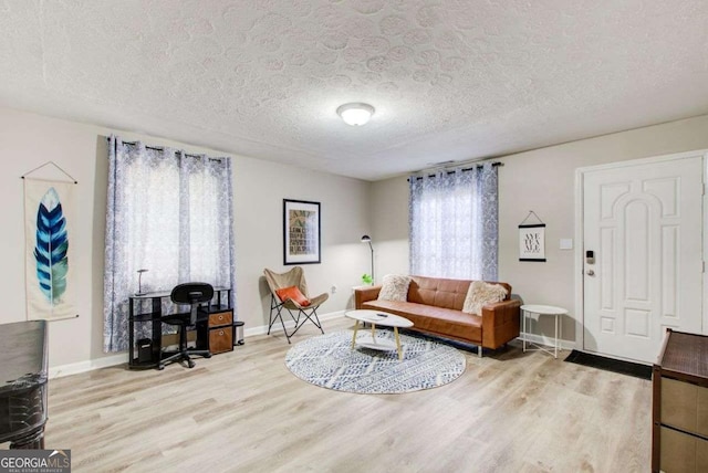 living area with a textured ceiling, baseboards, and wood finished floors