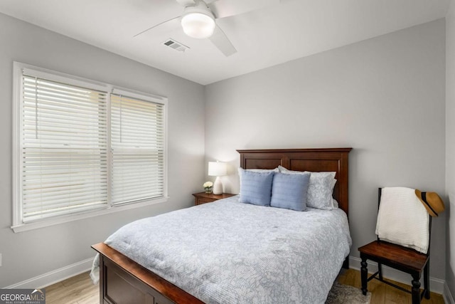 bedroom with light wood-type flooring, visible vents, baseboards, and a ceiling fan