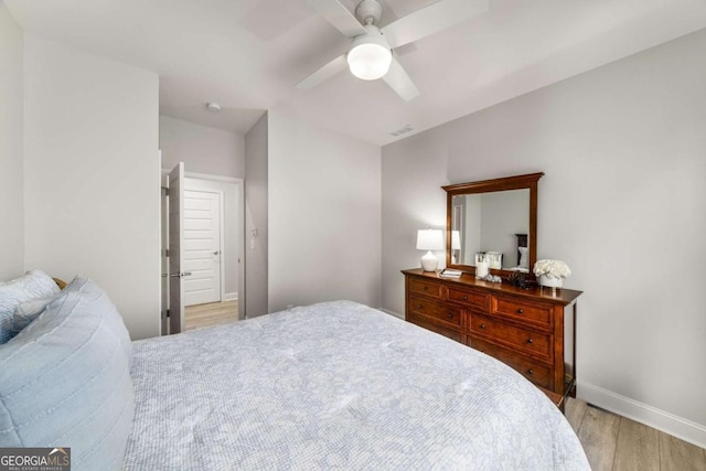 bedroom featuring a ceiling fan, baseboards, visible vents, and light wood-type flooring