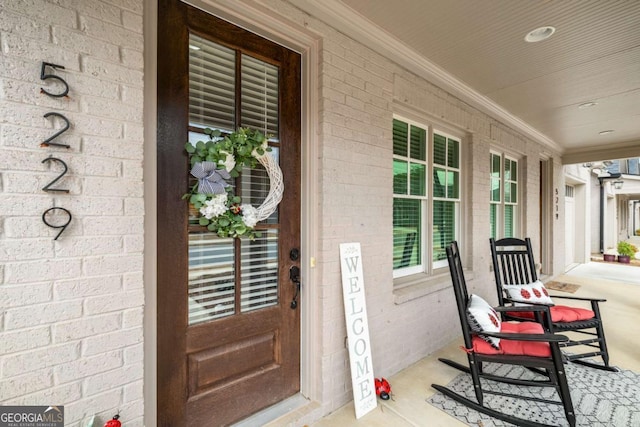 property entrance featuring brick siding and covered porch