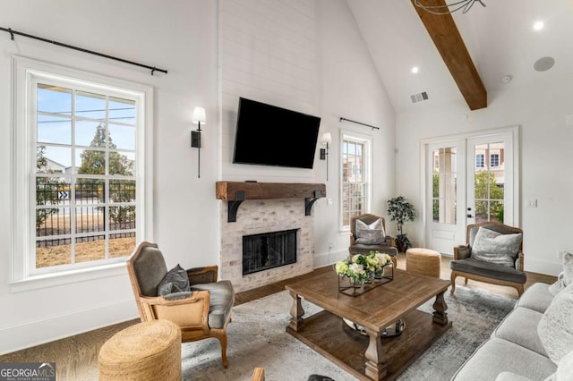 living room featuring visible vents, a large fireplace, beam ceiling, wood finished floors, and high vaulted ceiling