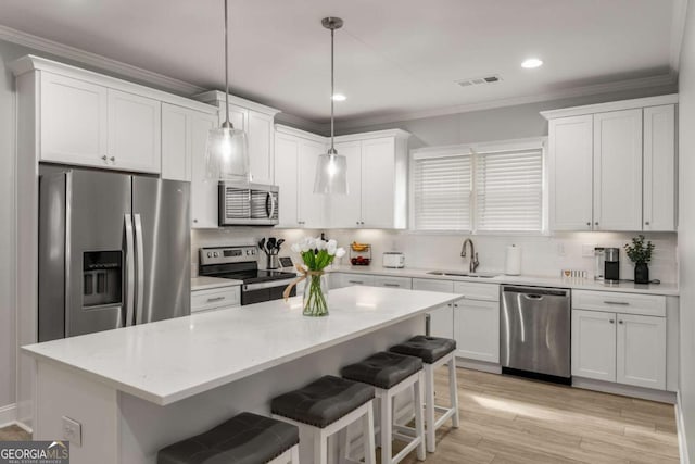 kitchen with visible vents, ornamental molding, a sink, appliances with stainless steel finishes, and white cabinetry