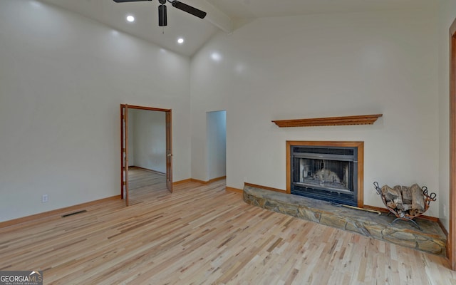 unfurnished living room featuring high vaulted ceiling, a stone fireplace, wood finished floors, visible vents, and beamed ceiling