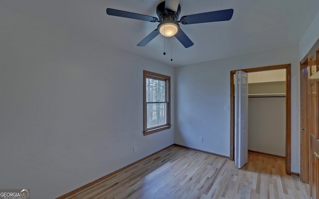 unfurnished bedroom featuring a ceiling fan, a closet, light wood-style flooring, and baseboards