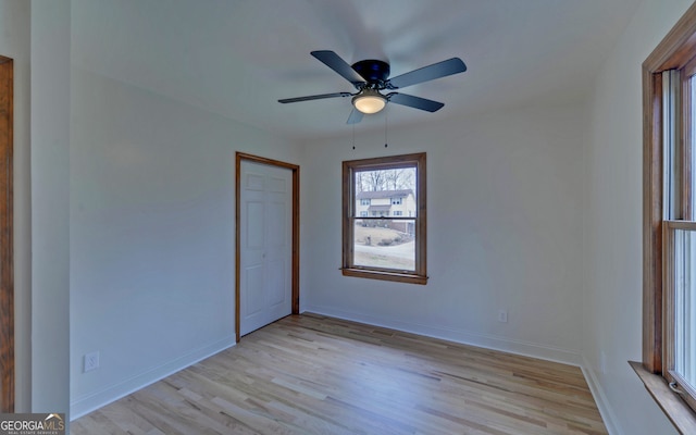 empty room with light wood-type flooring, ceiling fan, and baseboards