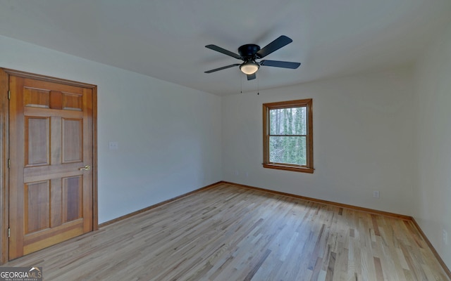 spare room with ceiling fan, light wood finished floors, and baseboards