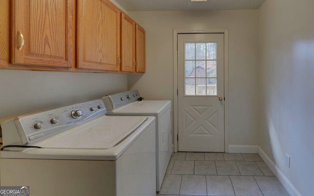 washroom featuring washer and clothes dryer, light tile patterned flooring, cabinet space, and baseboards