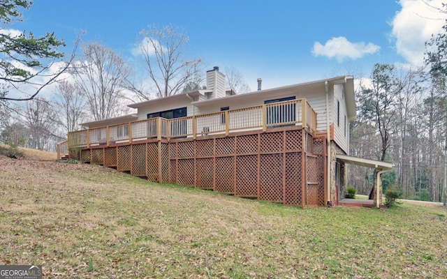 rear view of property featuring a wooden deck, a chimney, and a yard