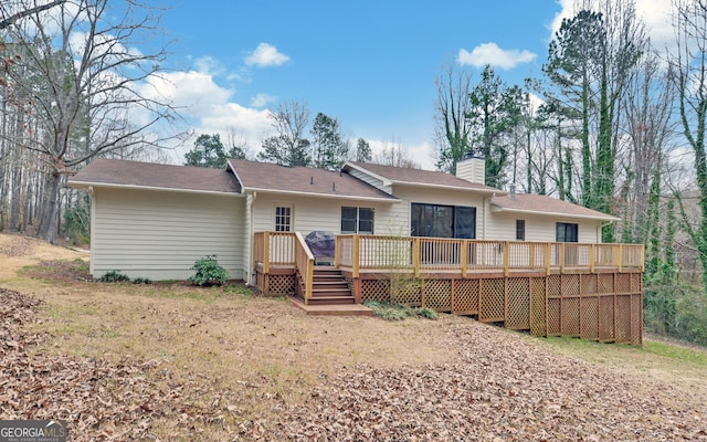 back of house with a chimney and a wooden deck