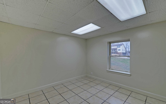 spare room with a drop ceiling, baseboards, and light tile patterned floors