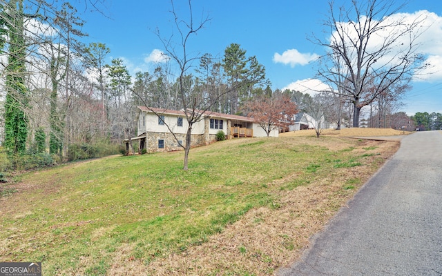 view of home's exterior featuring stone siding, a lawn, and an attached garage