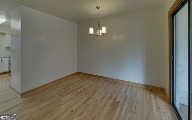 unfurnished dining area with light wood-type flooring, visible vents, baseboards, and an inviting chandelier