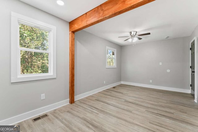 spare room featuring visible vents, ceiling fan, light wood finished floors, and baseboards