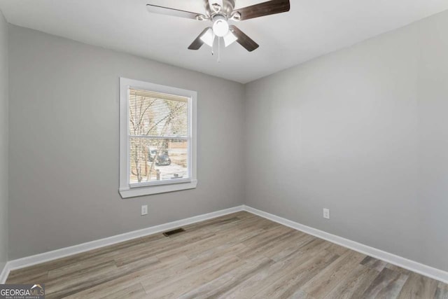 spare room featuring a ceiling fan, wood finished floors, visible vents, and baseboards