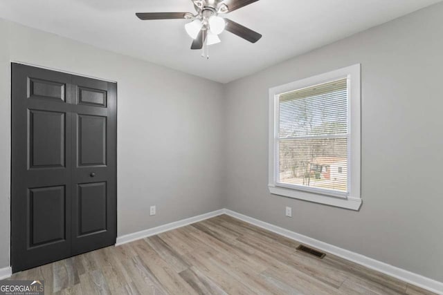 spare room with ceiling fan, light wood-style flooring, visible vents, and baseboards