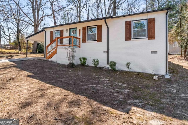 view of front facade with driveway, brick siding, and stairway