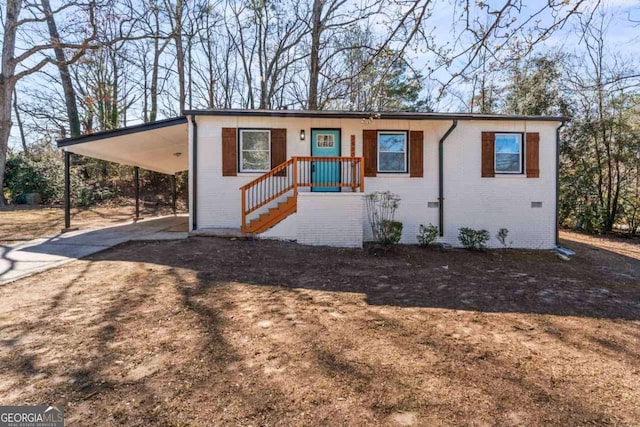 view of front of home featuring an attached carport, crawl space, brick siding, and driveway