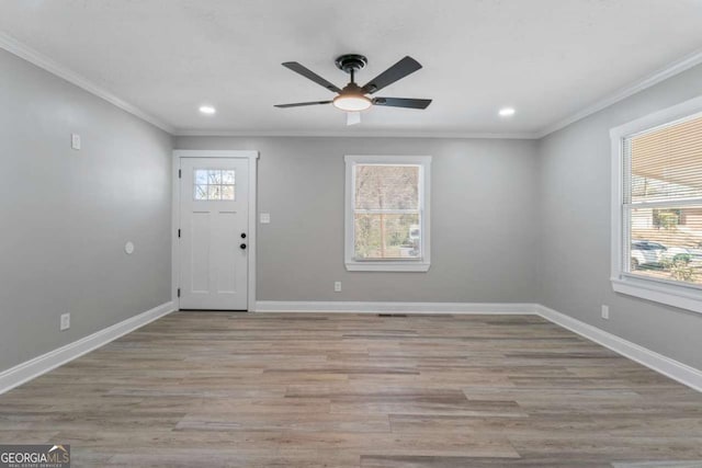 entryway with light wood-style floors, crown molding, plenty of natural light, and baseboards