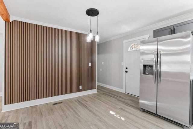 unfurnished dining area with ornamental molding, light wood-style flooring, visible vents, and baseboards