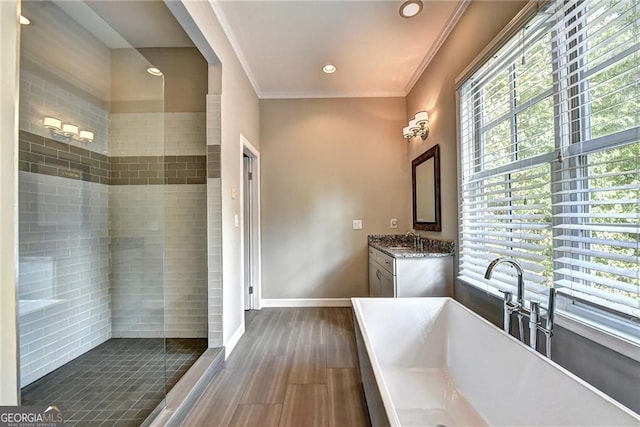 full bath with crown molding, baseboards, wood finished floors, a soaking tub, and vanity