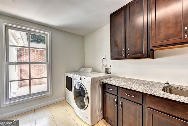 clothes washing area with light tile patterned floors, cabinet space, baseboards, and washer and clothes dryer