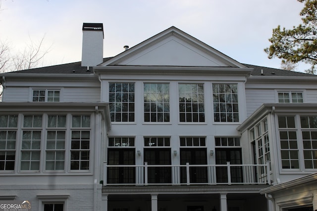 back of property with a balcony and a chimney