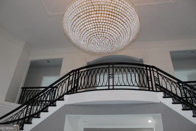 staircase with a high ceiling, a chandelier, and crown molding