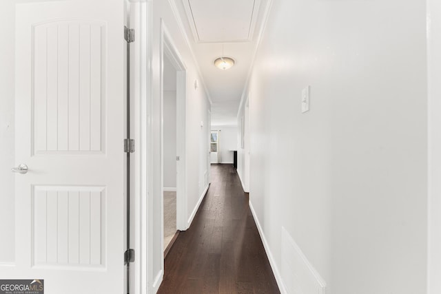 hall featuring dark wood finished floors, attic access, and baseboards