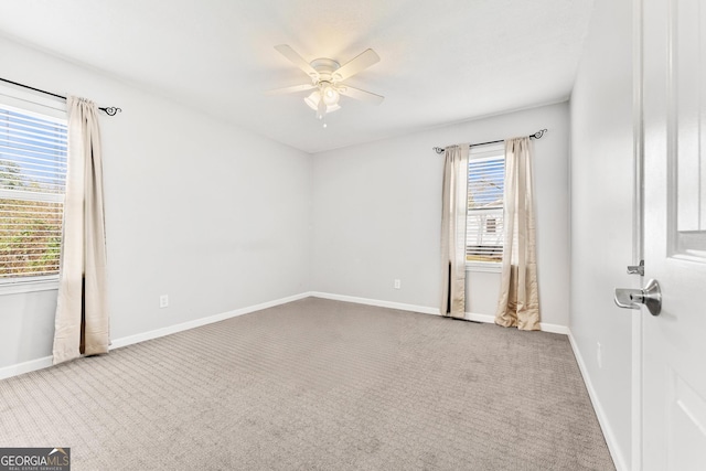 carpeted empty room with a ceiling fan and baseboards