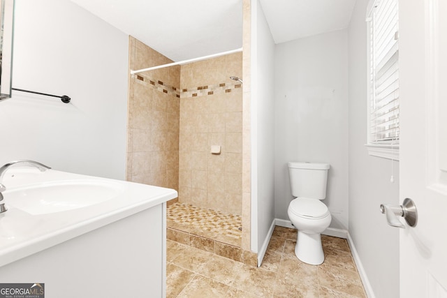 full bath featuring tiled shower, a sink, toilet, and baseboards