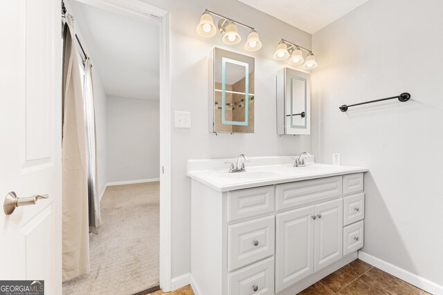 bathroom featuring tile patterned floors, a sink, baseboards, and double vanity