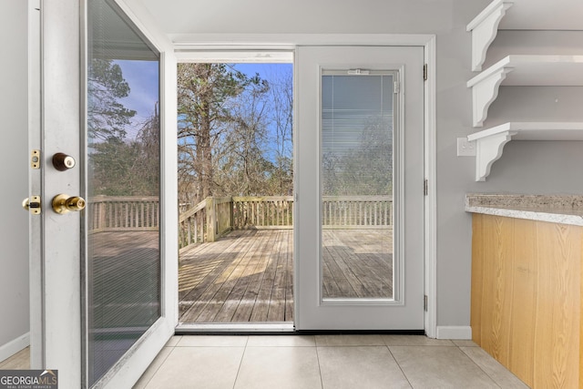 doorway with baseboards and light tile patterned flooring