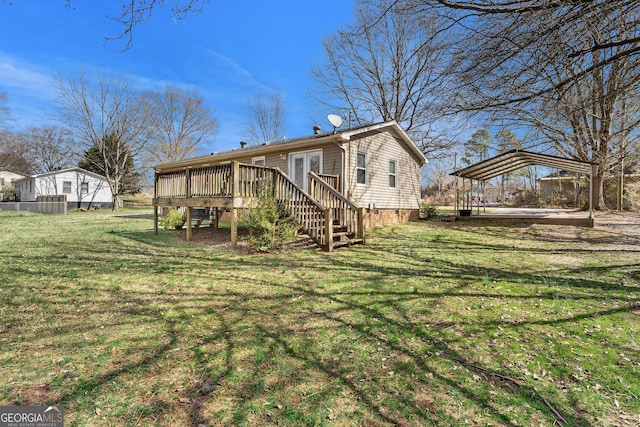 back of property with a deck, a detached carport, a lawn, and stairway