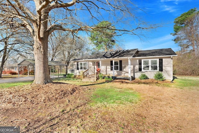 single story home featuring a porch, a detached carport, and a front lawn