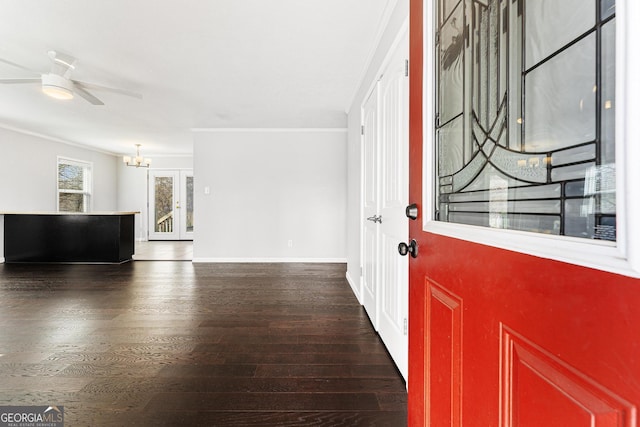 foyer featuring baseboards, ornamental molding, wood finished floors, and ceiling fan with notable chandelier